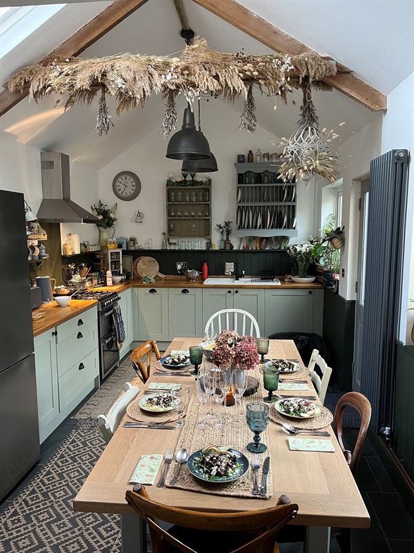 Kitchen and dining room with sage green cabinets and a dried-flower beam