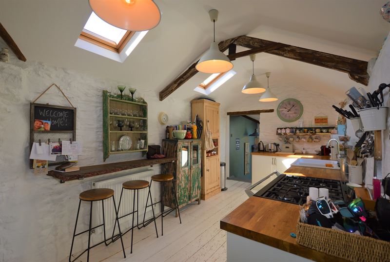 Open-plan kitchen with white walls, exposed beams and a breakfast bar