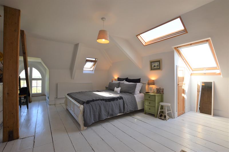 Attic bedroom with white painted floorboards and roof windows