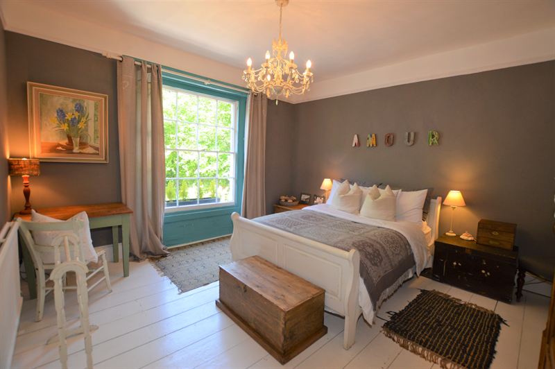 Bedroom with warm grey walls and a teal painted window frame